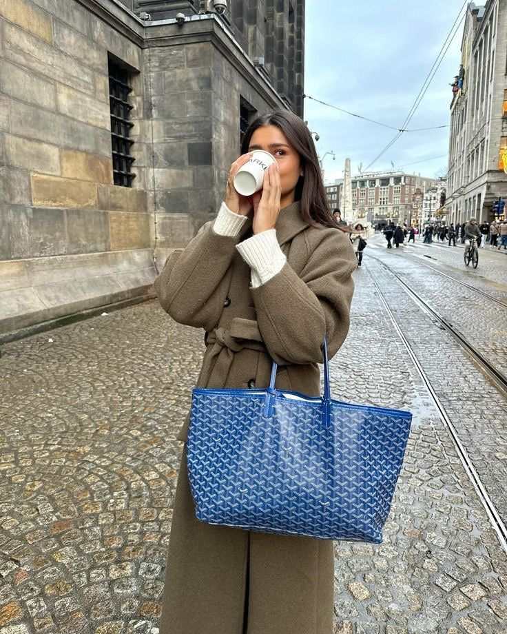 Woman holding blue Élodie Tote Bag in city street drinking coffee