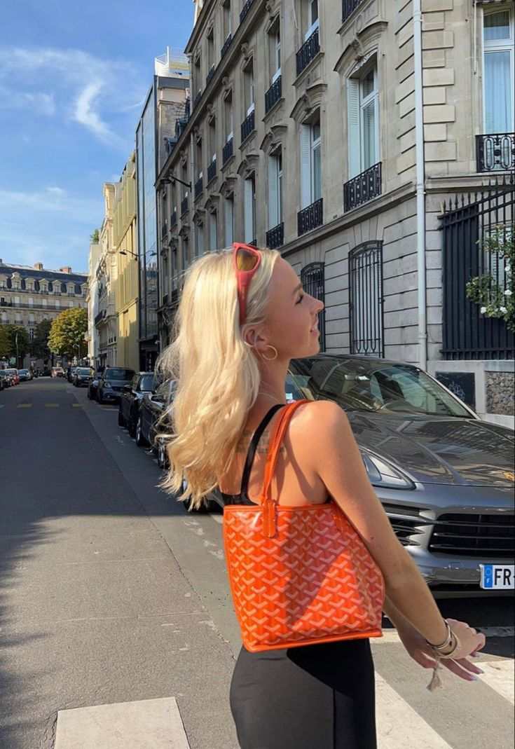 Woman carrying orange Élodie Mini Tote with geometric pattern on city street