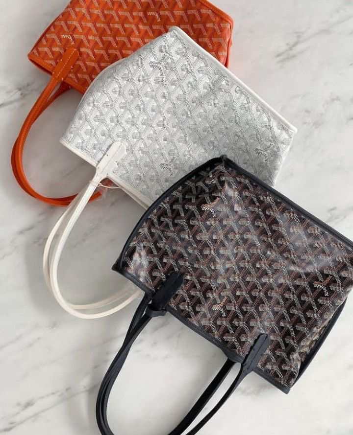 Three chic Élodie Mini Tote bags in orange, white, and black with geometric patterns and double handles on a marble surface.