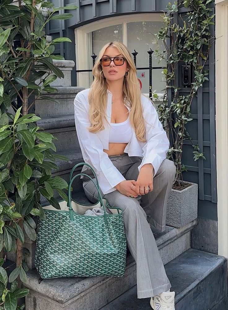 Woman sitting outdoors holding green Élodie tote bag with matching pouch in patterned finish